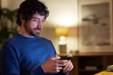 Man bekijkt smartphone terwijl hij in de zetel zit