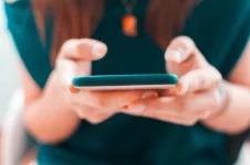 Vrouw houdt gsm in de hand en bekijkt of ze kan overstappen van provider.