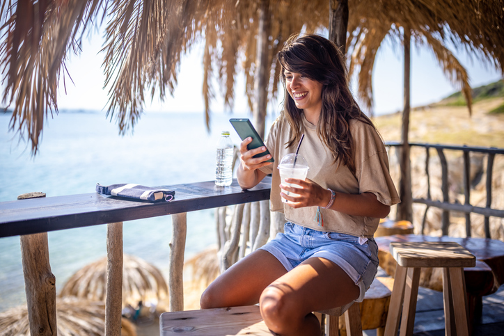 Vrouw kijkt op haar telefoon in een strandbar
