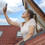 Vrouw zoekt gsm-signaal uit dakraam