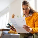 Vrouw kijkt naar factuur met smartphone in de hand