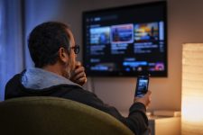 Man bekijkt app op smartphone om tv te bedienen