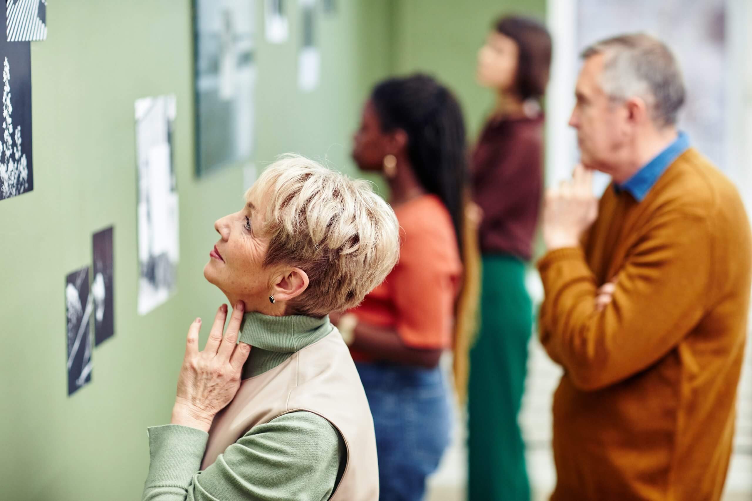 Vrouw en man kijken naar zwartwitte fotocollectie om muur.