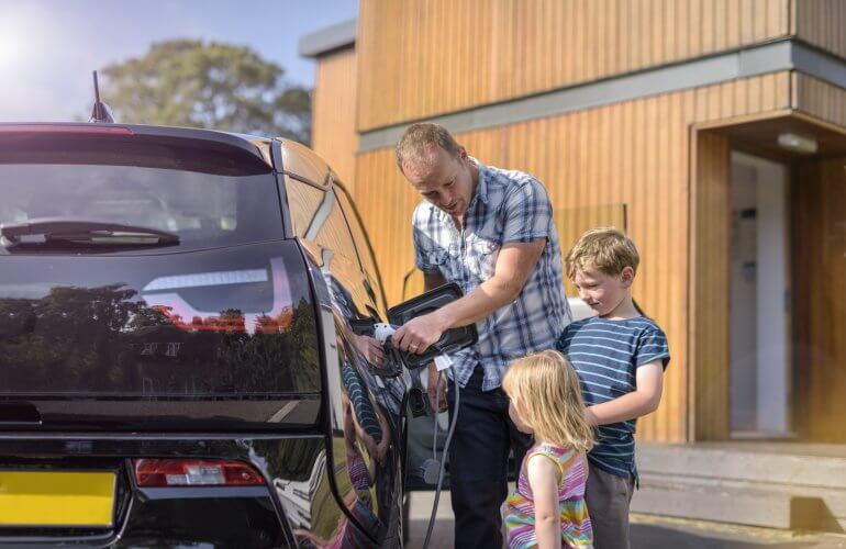 Vader en kinderen laden de auto op met een laadpaal.