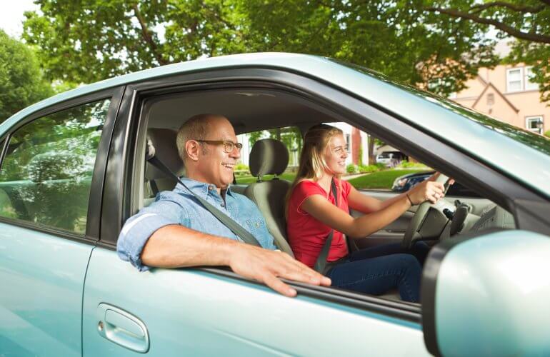 Dochter rijdt met de auto terwijl haar vader passagier is.