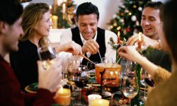 Mensen zitten rond tafel en eten fondue tijdens Kerstmis