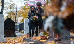 Koppel rouwt bij graf van overleden familielid.
