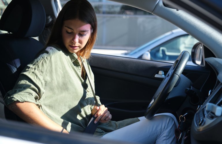 Vrouw doet haar gordel om in de auto.