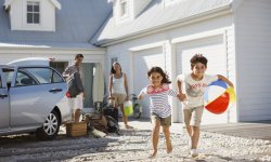 Familie-komt-toe-bij-hun-vakantiehuisje-en-kinderen-lopen-met-strandballen-rond